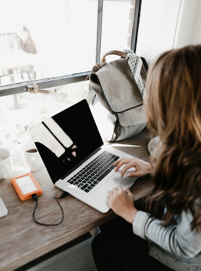 Woman working on a laptop at a wooden table