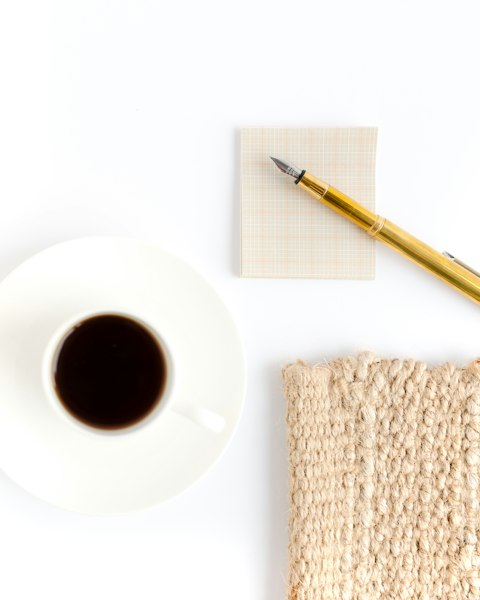 Coffee, notebook and pen on a white table