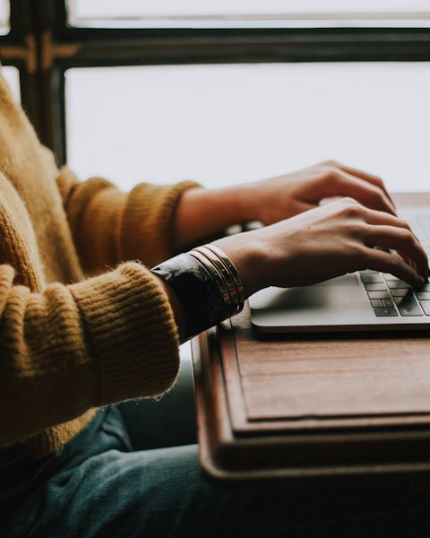 Hands typing on a laptop